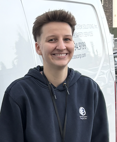 Smiling person with short hair wearing a navy hoodie.