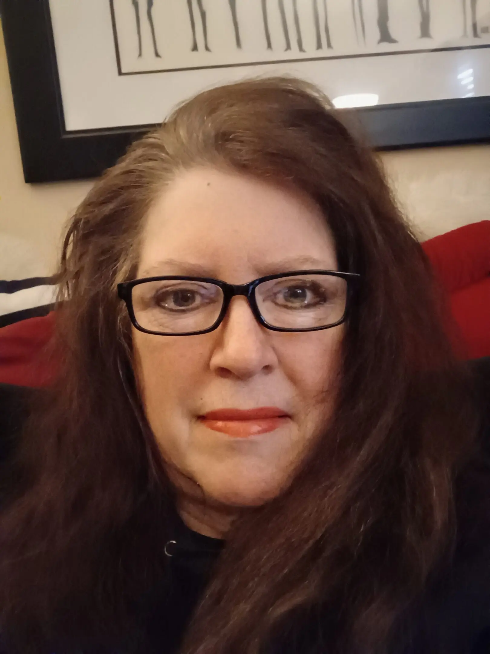 Woman with glasses and long brown hair smiling gently.
