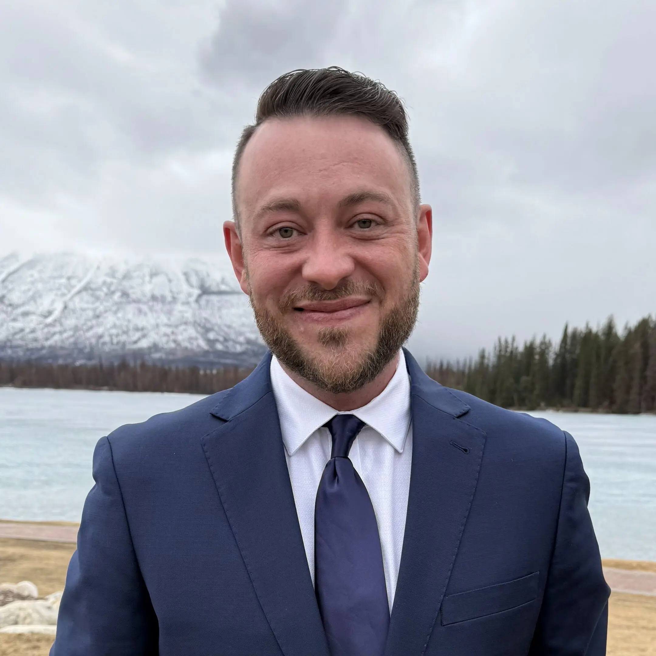 A man in a navy blue suit smiling.