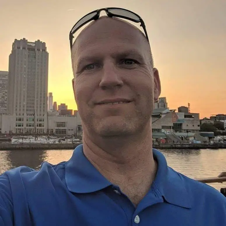Man wearing blue shirt taking waterfront selfie